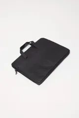 Funda para laptop de diseño minimalista en color negro, con cierre perimetral y manijas superiores para un transporte cómodo.