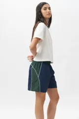 Short deportivo negro con detalles en verde militar, cintura elastizada, bolsillos laterales y ribete blanco.