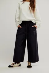 Pantalón de denim negro de tiro medio, con cintura elástica ajustable mediante cordón, bolsillos frontales tipo plaqué y corte amplio y relajado de pierna ancha.