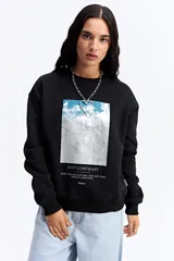 Buzo de algodón color beige con cuello redondo y estampa central rectangular en tonos rosa y dorado. Presenta un diseño de calce relajado con puños y ruedo acanalados.