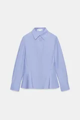 Camisa de algodón con cuello solapa, manga larga con puños y diseño peplum en el bajo. Presenta cierre frontal con botones ocultos por solapa.