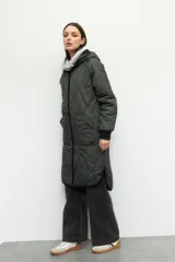 Campera de nylon larga oversized color negro, con capucha, tres bolsillos externos y uno interno. De tela capitoneada, con puños en las mangas y forro polar.