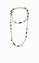 Collar largo de diseño en capas, elaborado en metal con acabado dorado. Presenta una estructura de cadena fina intercalada con aplicaciones de perlas blancas y piedras cuadradas en tonos rojizos y oscuros.