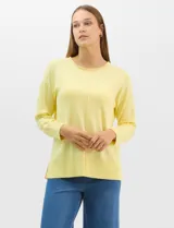 Buzo de tejido fino color amarillo, con cuello redondo, manga larga con puños acanalados y pespunte central vertical en el frente y la espalda. Presenta un ruedo ancho acanalado con tajos laterales.