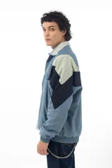 Campera deportiva azul con recortes en negro y verde agua, cierre frontal con cremallera y cuello tipo mao.