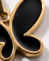 Dije de acero con baño de oro y diseño de mariposa con relleno de esmalte negro.