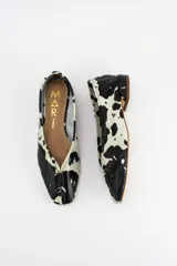 Mocasines de cuero con estampado animal print tipo vaca en blanco y negro, con costura central en la capellada y taco bajo.