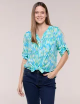 Blusa camisera de estilo casual confeccionada en mezcla de rayón y poliéster, con estampado multicolor en tonos turquesa, verde y celeste. Presenta escote en V con cuello mao, abotonadura frontal con botones nacarados, bolsillos aplicados en el pecho y mangas tres cuartos con presilla para arremangar. Cuenta con ruedo curvo y picos frontales diseñados para anudar en la cintura.