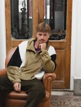 Buzo afelpado color verde oliva, blanco y negro con cuello polo abotonado.