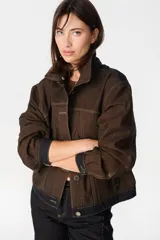 Chaqueta de denim color marrón con costuras en contraste, cuello de lana desmontable en color crema, cierre frontal con botones metálicos y bolsillos laterales.