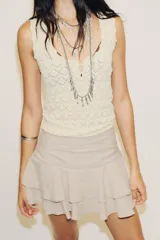 Falda pantalón corta color beige claro, de tiro medio, con efecto drapeado en la cintura y volantes superpuestos en el ruedo.