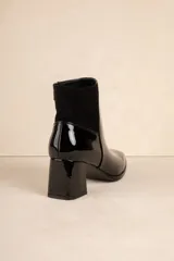 Botas de caña baja color negro, de símil cuero con punta redonda, cierre lateral, taco cuadrado y recorte en gamuza en la parte trasera.