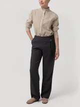 Pantalón gris de tiro alto y corte recto, confeccionado en mezcla de lana y poliéster reciclado. Presenta pretina limpia con cierre invisible lateral y un botón decorativo en el lateral.