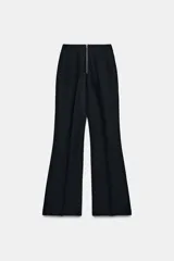 Pantalón de tiro alto en color negro, con diseño de corte recto y ligeramente acampanado. Presenta costuras verticales marcadas en el frente y bolsillos laterales de vivo.