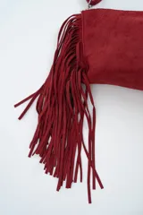Cartera tipo sobre de gamuza color rojo, con detalle de flecos largos en uno de sus laterales y correa larga ajustable.