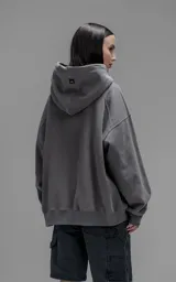Hoodie oversize de corte crop, color gris oscuro, confeccionado en frisa de algodón. Presenta capucha forrada, bolsillo tipo canguro frontal y puños elásticos.