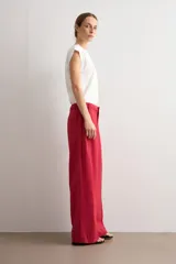 Pantalón de corte recto y pinzas delanteras, color rojo, con bolsillos laterales y cierre frontal con botón y cremallera.