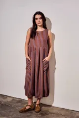 Vestido maxi sin mangas de corte fluido, con diseño a rayas verticales en tonos azul y marrón. Presenta cuello redondo y bolsillos frontales aplicados.