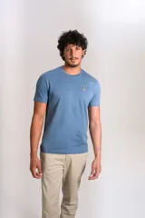 Remera de cuello redondo y manga corta en color azul, con un pequeño bordado de un pingüino esquiando en el pecho.
