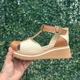 Sandalias de cuero en combinación de tonos marrón y marfil, con diseño de punta cerrada, tiras en forma de T y plataforma corrida dentada.
