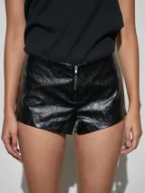 Short negro de cuero sintético con acabado brillante y cierre frontal.