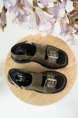 Sandalias de cuero texturizado en color verde oliva, con diseño de tiras anchas y hebilla metálica frontal con ojales. Presentan suela track negra y ajuste con velcro en el talón.