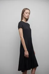 Vestido midi negro confeccionado en viscosa, de corte evasé, mangas cortas y escote redondo.