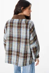 Chaqueta de corte holgado con estampado de cuadros en tonos beige, marrón y amarillo. Presenta cuello camisero en pana marrón, cierre frontal con botones y mangas largas con puños abotonados.