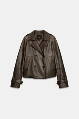 Cazadora de Zara Woman Collection confeccionada en material efecto piel color marrón oscuro. Presenta cuello con solapas, cierre frontal cruzado con botones, bolsillos delanteros y mangas largas con trabillas y hebillas ajustables en los puños.