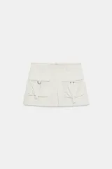 Falda pantalón satinada de tiro medio en color beige, con bolsillos cargo de plastrón con solapa en el delantero, detalles de pliegues y cierre lateral con cremallera oculta.