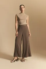 Pantalón ancho color marrón oscuro, de silueta fluida y cintura elastizada. Presenta una pretina ancha con botones metalizados irregulares.