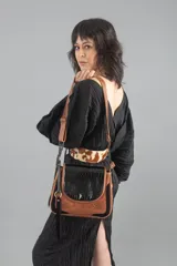 Cartera bandolera de cuero marrón con solapa de cuero negro con textura de cocodrilo.