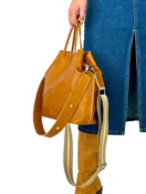 Bolso tote color marrón cuero, confeccionado en cuero genuino, con doble asa de mano y correa bandolera de tela con rayas beige y marrón.