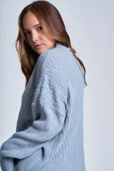 Sweater color crema con cuello alto y diseño de trenzas.