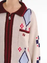 Campera tejida en jacquard con cierre frontal, cuello tipo polo y bolsillos delanteros. Diseño multicolor con estampado geométrico de rombos y detalles bordados a mano.