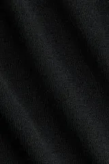 Top de punto fino color negro, de manga larga, con hombros descubiertos y detalle cruzado en el escote.