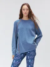 Remera de manga larga de corte clásico y calce suelto, color azul con efecto deslavado y cuello redondo a la base. Cuenta con costuras pespunteadas en tono contrastante en las sisas, las mangas y el frente, y un pequeño logo bordado en la esquina inferior.