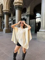 Poncho de hilo liviano en color crema, con diseño de cuello redondo y caída fluida, ideal para media estación.