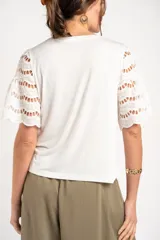 Remera blanca oversize con mangas cortas de encaje perforado con detalles bordados.