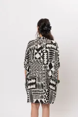 Camisa oversize de manga corta, con diseño estampado geométrico en blanco y negro, escote en V con cuello mao y cierre frontal con botones.