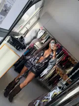 Vestido corto de tul con estampado batik en tonos marrones y negros. Presenta un escote profundo en V, mangas largas acampanadas y un detalle de nudo frontal con lazo que ajusta la cintura.
