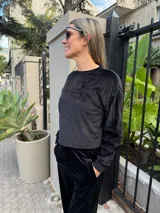 Buzo cropped de cuello redondo y manga larga, confeccionado en tejido plush negro con textura ultrasuave y acabado aterciopelado.