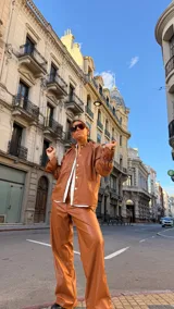 Camisa de cuero sintético color marrón, con cuello redondo, cierre frontal de botones y mangas largas con diseño fruncido y volados en los puños.