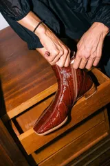 Botinetas de cuero con textura croco acharolado en color negro. Presentan un diseño de punta cuadrada, cierre lateral y un taco bajo de madera.