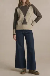 Sweater de punto color marrón oscuro y beige, con diseño de rombos en el parte frontal. Tiene cuello redondo y mangas largas con puños acanalados.