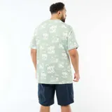 Camiseta de manga corta y cuello redondo en color verde, con estampado integral de palmeras y paisajes tropicales en tono claro.