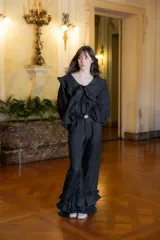 Pantalón de lino color negro, de corte recto y holgado, con detalle de volados en el ruedo y cierre frontal con botón de nácar.