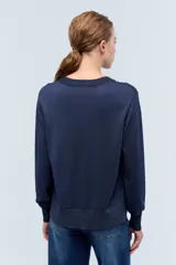 Sweater azul marino de tejido de punto con cuello redondo y mangas largas. Presenta pequeños apliques brillantes en el frente y la espalda.