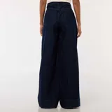 Jean de corte wide leg en color azul oscuro, con diseño de cinco bolsillos y costuras verticales decorativas en el frente. Presenta un tiro alto con cierre de botón y cremallera.
