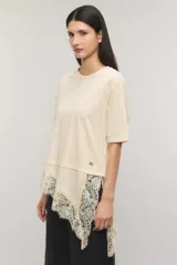 Remera negra de corte oversize, con escote redondo, mangas cortas y detalle de tajo irregular con terminación en puntilla en el ruedo. Confeccionada en jersey de algodón.